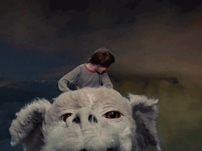 An animated gif of Bastian Bux and Falkor from the movie 'The Neverending Story'. In the gif Bastian is flying through the air on Falkor's back and punching his fist into the air victoriously.