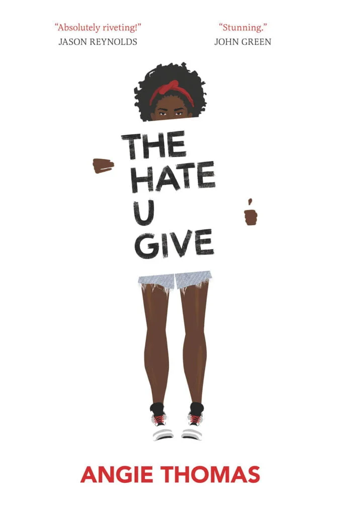 The front cover of the book 'The Hate U Give'. It features a black girl holding a sign with the title of the book written across it.
