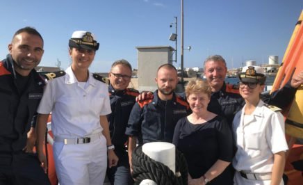 Claire Mallinson with members of the Italian Coast Guard who work to protect people at sea. &copy; AI