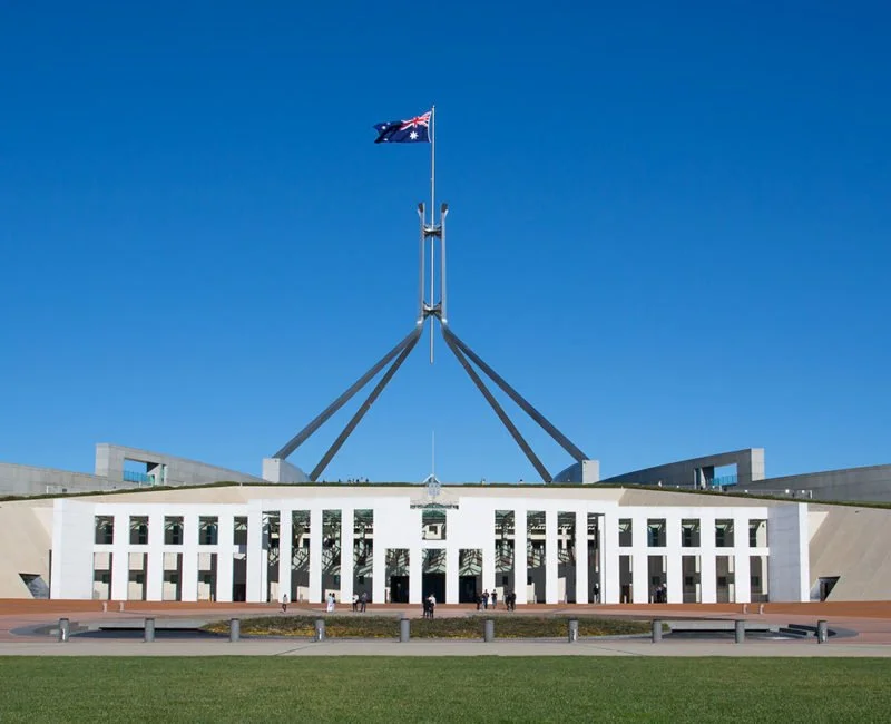 A photo of Parliament House in Canberra, set against a deep blue sky