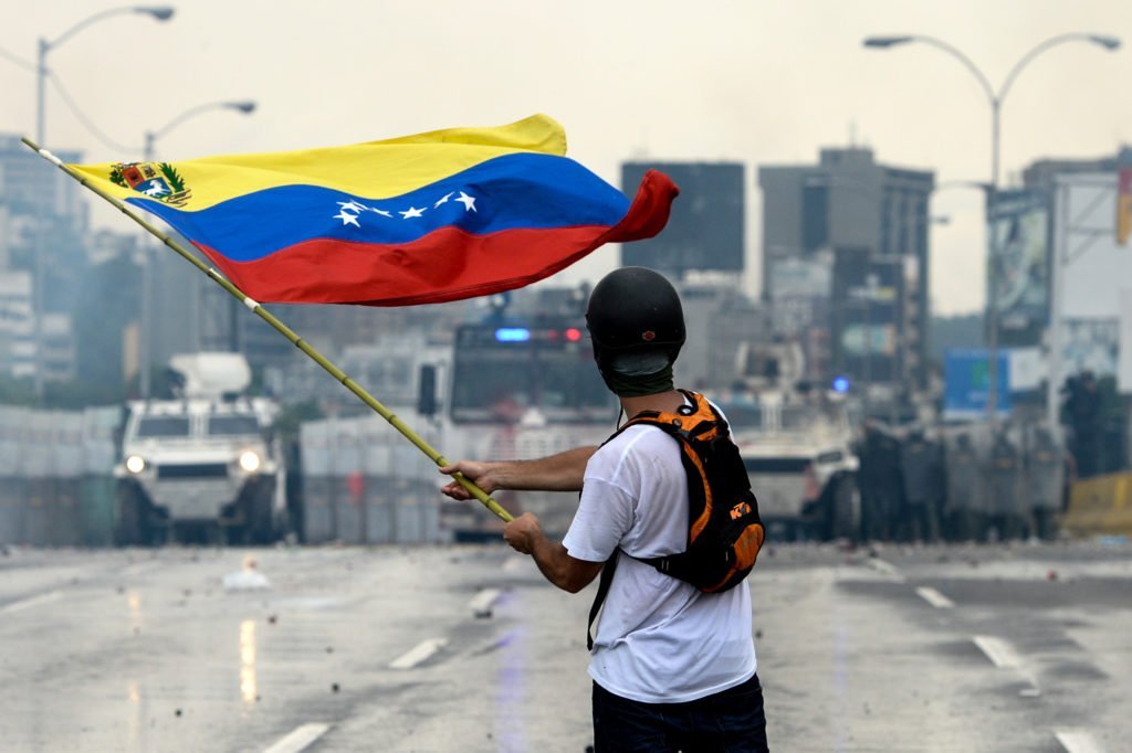 VENEZUELA: An opposition demonstrator waves a flag at the riot police in a clash during a protest against President Nicolas Maduro, in Caracas on May 8, 2017. © FEDERICO PARRA/AFP/Getty Images