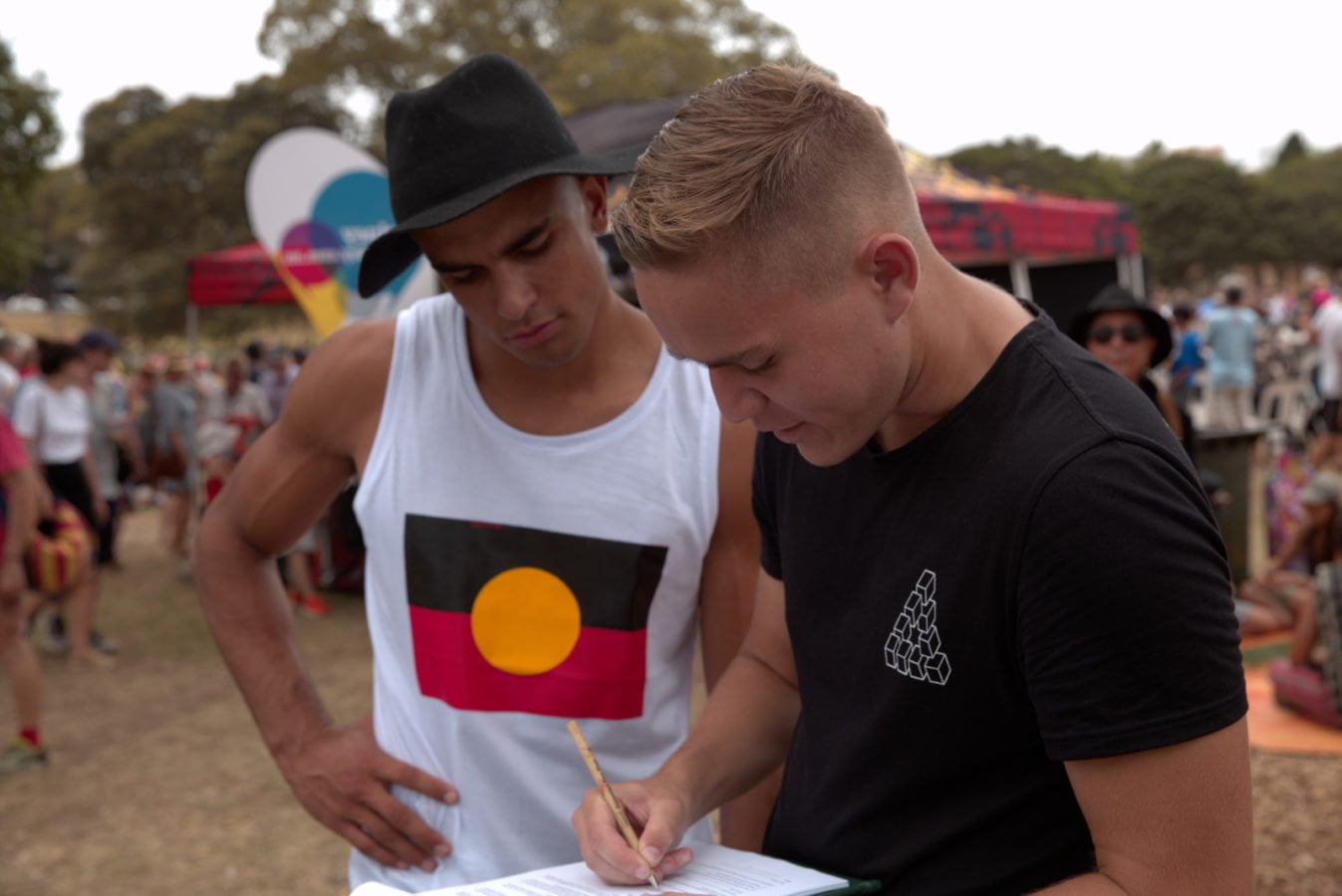 Two young Indigenous men signing an Amnesty petition at Yabun festival on Survival Day in Sydney