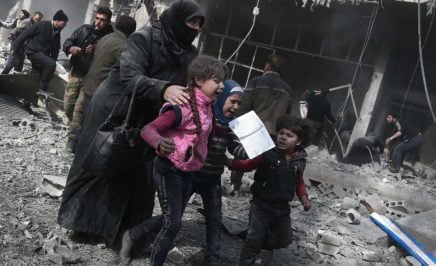 A Syrian woman and children run for cover amid the rubble
