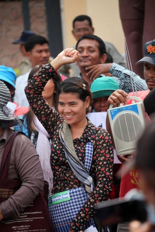 Tep Vanny, one of 13 women Boeung Kak Lake activists sentenced to jail after a peaceful protest, stands with her arm in the air, fist clenched, with a smile on her face.