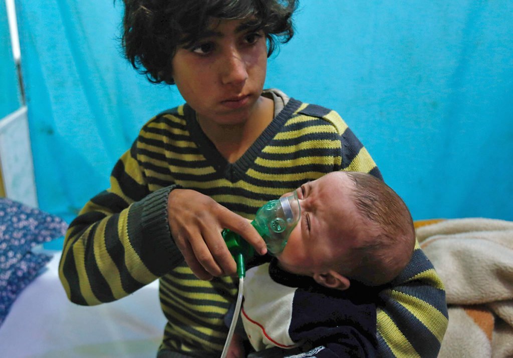 A Syrian boy holds an oxygen mask over the face of an infant at a make-shift hospital following a reported gas attack in Eastern Ghouta.