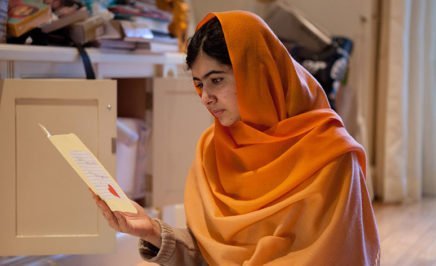 Young woman with an orange hijab reading a book