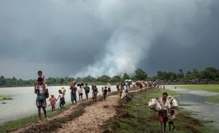Rohingya refugees stream into Bangladesh after crossing the Naf River, which separates Myanmar and Bangladesh, in September 2017. In the background, smoke rises from villages being burned in northern Rakhine State, Myanmar.