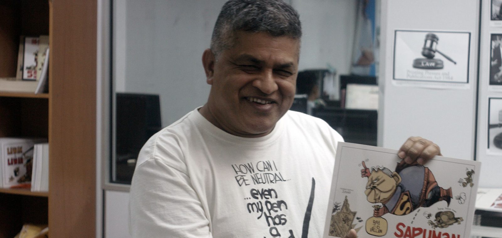 Zunar holding his book 'Sapuman, Man of Seel'. © Amnesty International