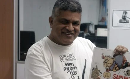Zunar holding his book 'Sapuman, Man of Seel'. © Amnesty International