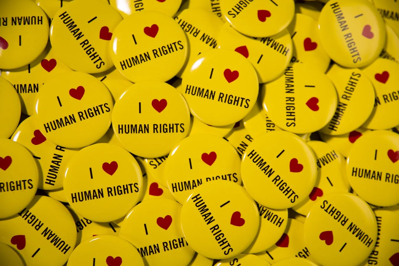 Hundreds of yellow badges with 'I heart human rights' printed on them.