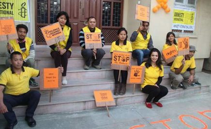 A group of people wearing yellow t-shirts and holding signs that say 'Stop violence against women'.