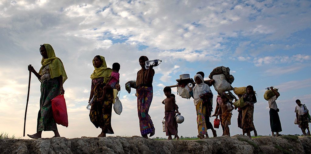 Image of Rohingya refugees walking through a field in Bangladesh.