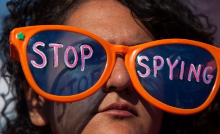 A woman wearing a pair of glasses with 'Stop spying' written on the lenses.