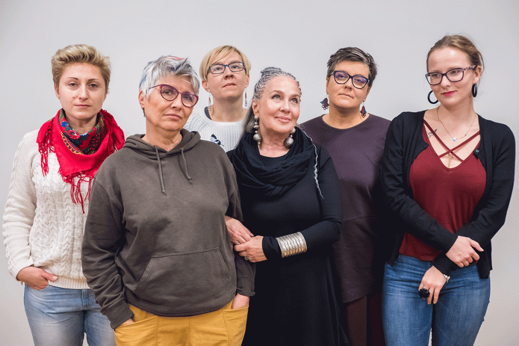 Six women of different age groups look defiantly at the camera.