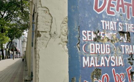 Pedestrian walks past grim message of Malaysia's death penalty