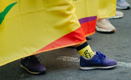 Foot wearing Amnesty sock behind pride banner