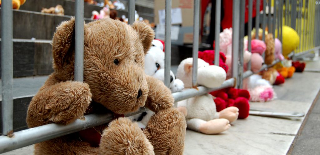 Fluffy teddy bears in a row, looking out of prison bars