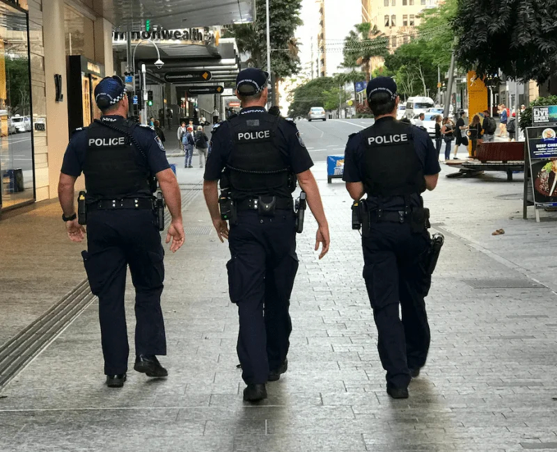 Three uniformed police officers walk the street in QLD.
