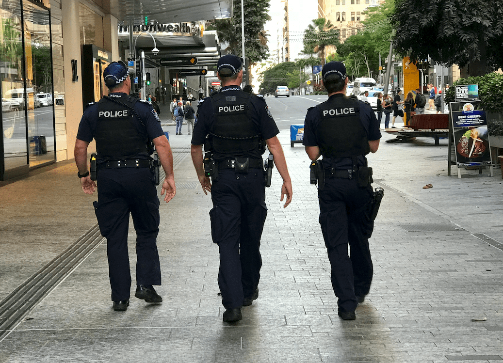Three uniformed police officers walk the street in QLD.