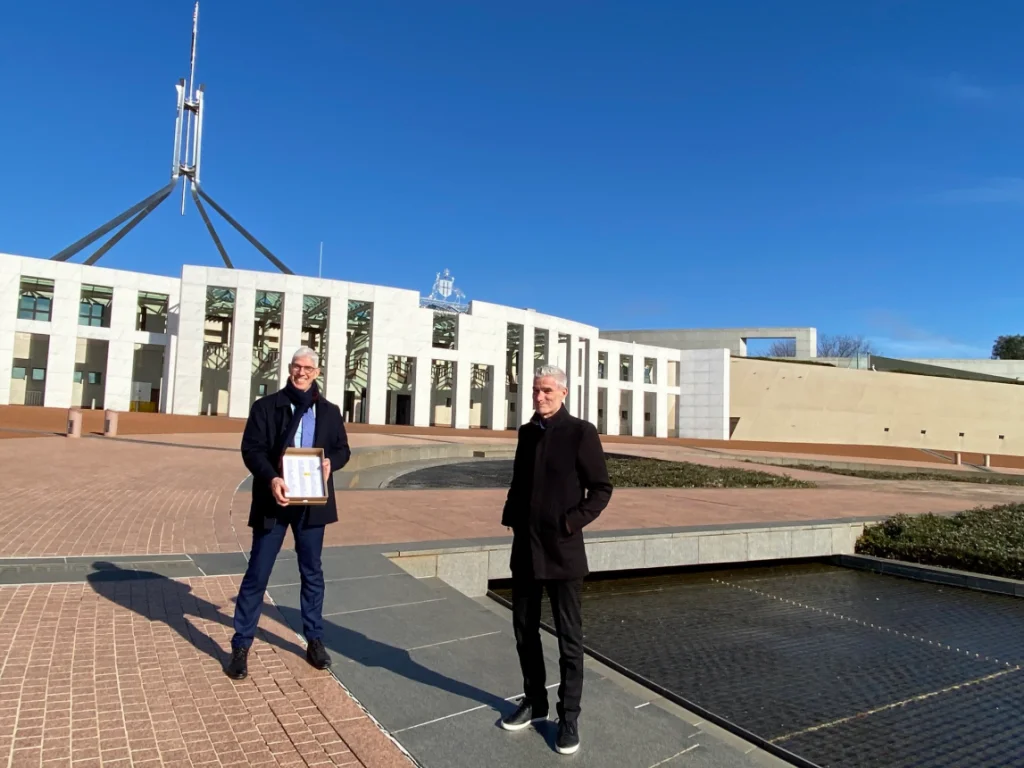 Craig Foster and Dr Graham Thom stand in front of Australian Parliament with petitions