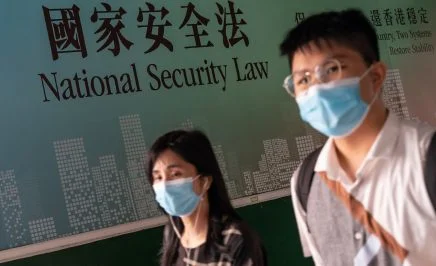 Two people wearing masks walk past a sign that reads 