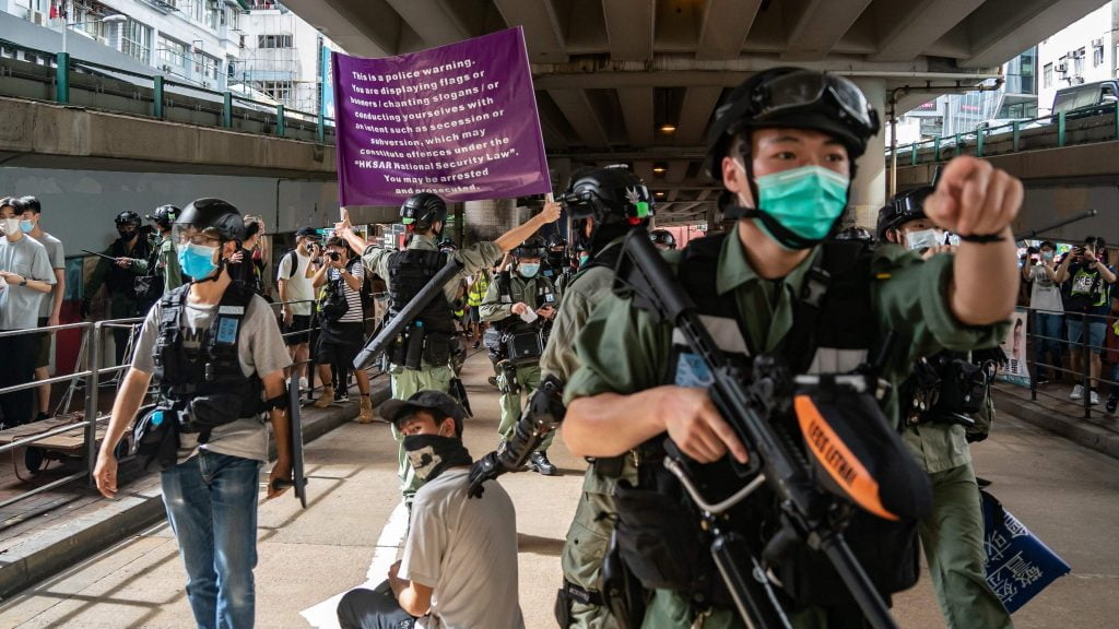 Riot police detain a man at a demonstration as they raise a purple warning flag on the national security law during a demonstration in Hong Kong.