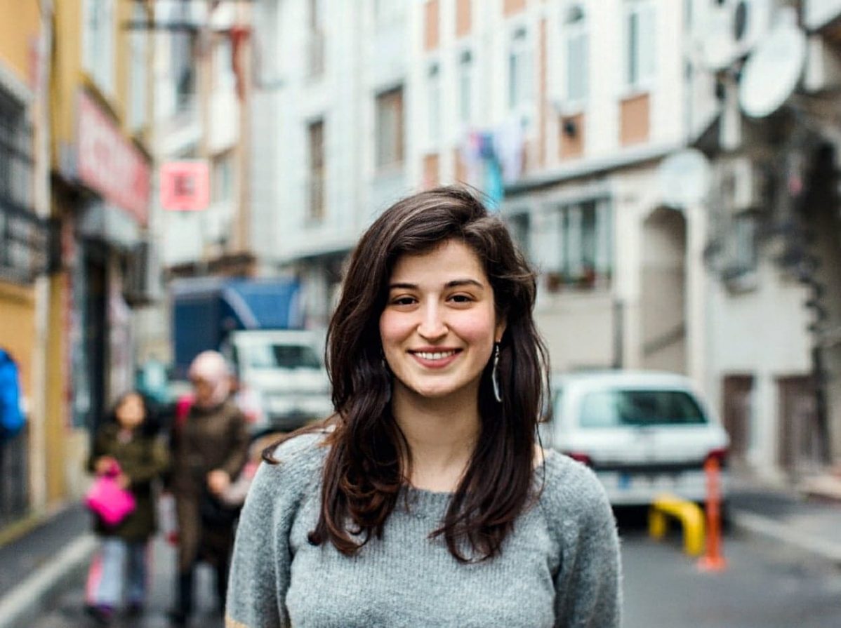 A portrait of Refugee Activist Samah Shda, smiling in the street.