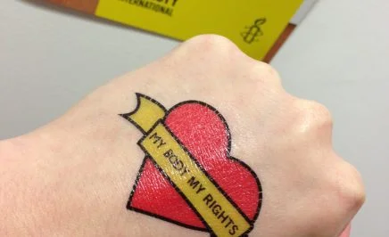A hand with a love heart tattoo and the words 