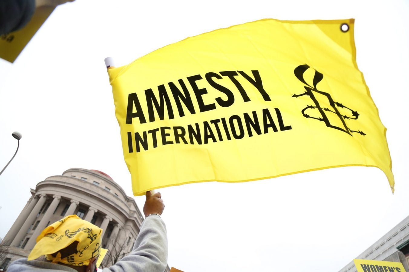 Image of a yellow and black flag, featuring the Amnesty International logo, being waved.