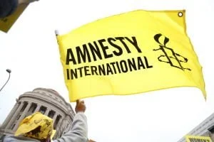 Image of a yellow and black flag, featuring the Amnesty International logo, being waved.