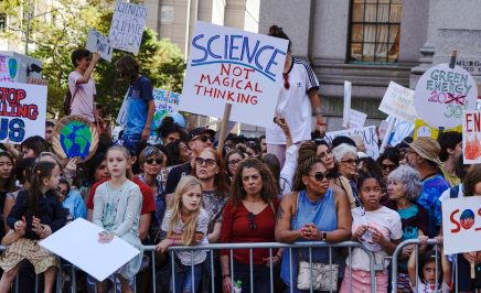 Climate protest with people behind banisters holding a sign that say 