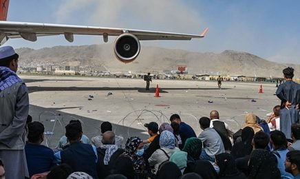 People sit as they wait to leave the Kabul airport in Kabul on August 16, 2021, after a stunningly swift end to Afghanistan's 20-year war, as thousands of people mobbed the city's airport trying to flee the group's feared hardline brand of Islamist rule.