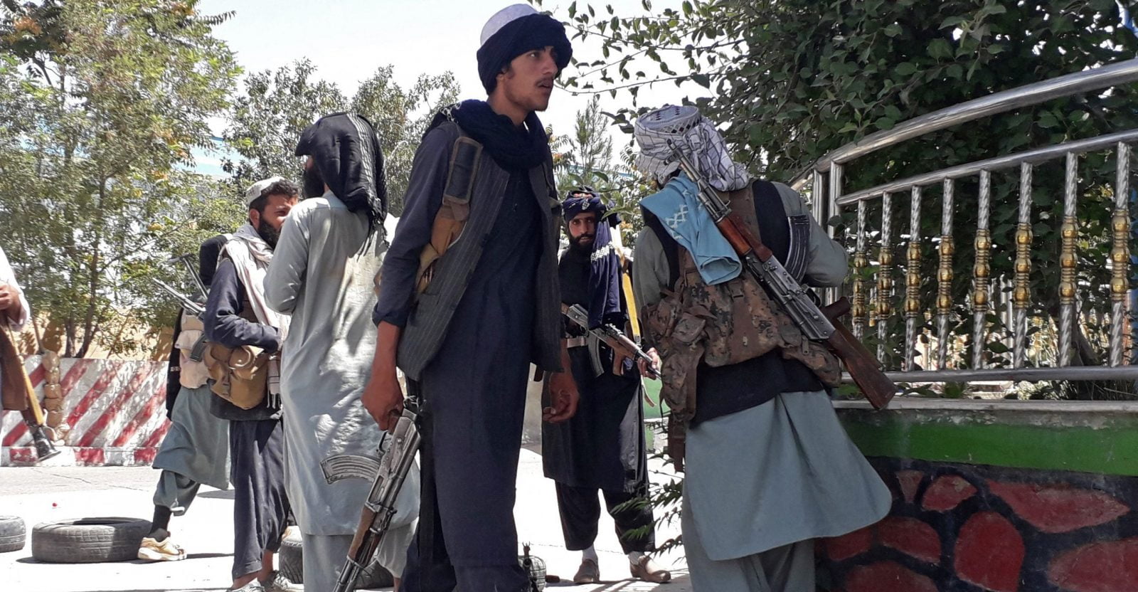 Taliban fighters armed with guns stand along the roadside in Ghazni