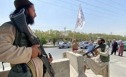 Taliban fighters stand guard at an entrance gate.