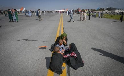 Afghan family huddled in the middle of the airport tarmac.