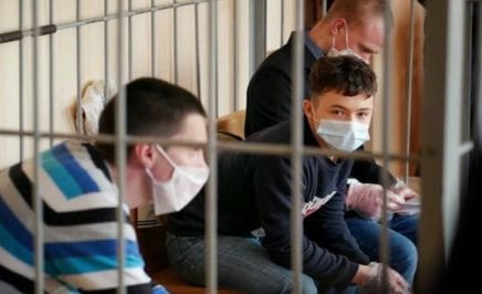image of a young boy wearing a mask behind bars
