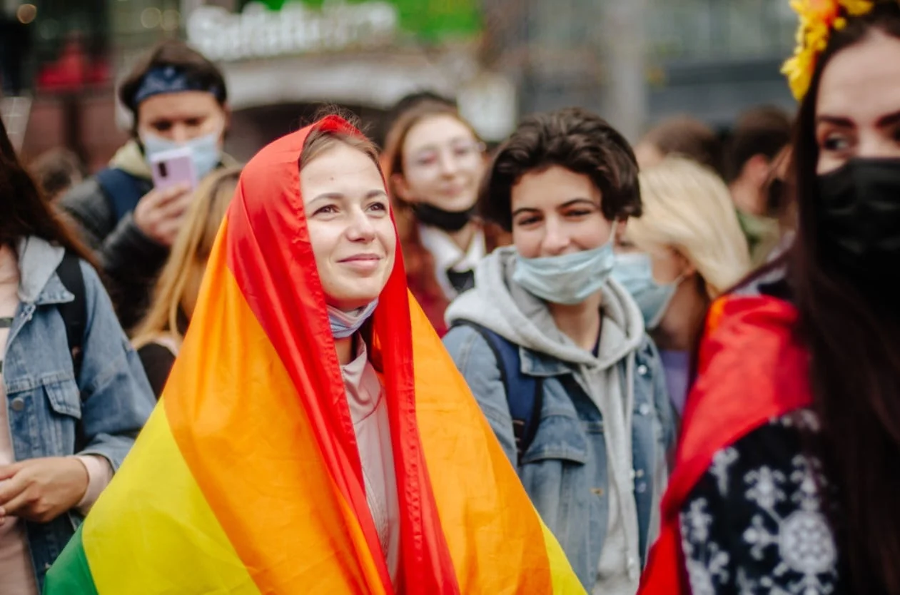 Wide shot of a group of women activists in Kyiv Pride march in 2021. One woman has a rainbow flag draped on her person.