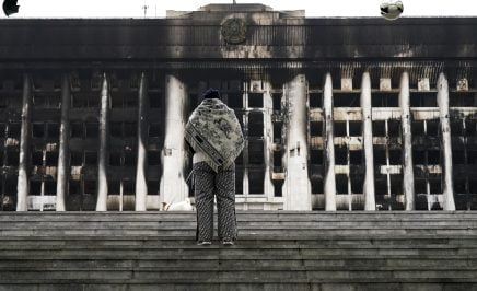 An image of a person standing in front of a scorched building in Almety Kazakhstan