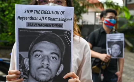Human rights protestor holds sign to camera which reads 'Stop the execution of Nagaenthran K Dharmalingam #SaveNagaenthran