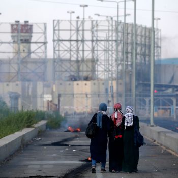 Three Palestinian protestors walk towards the border during a demonstration at the Erez crossing with Israel.