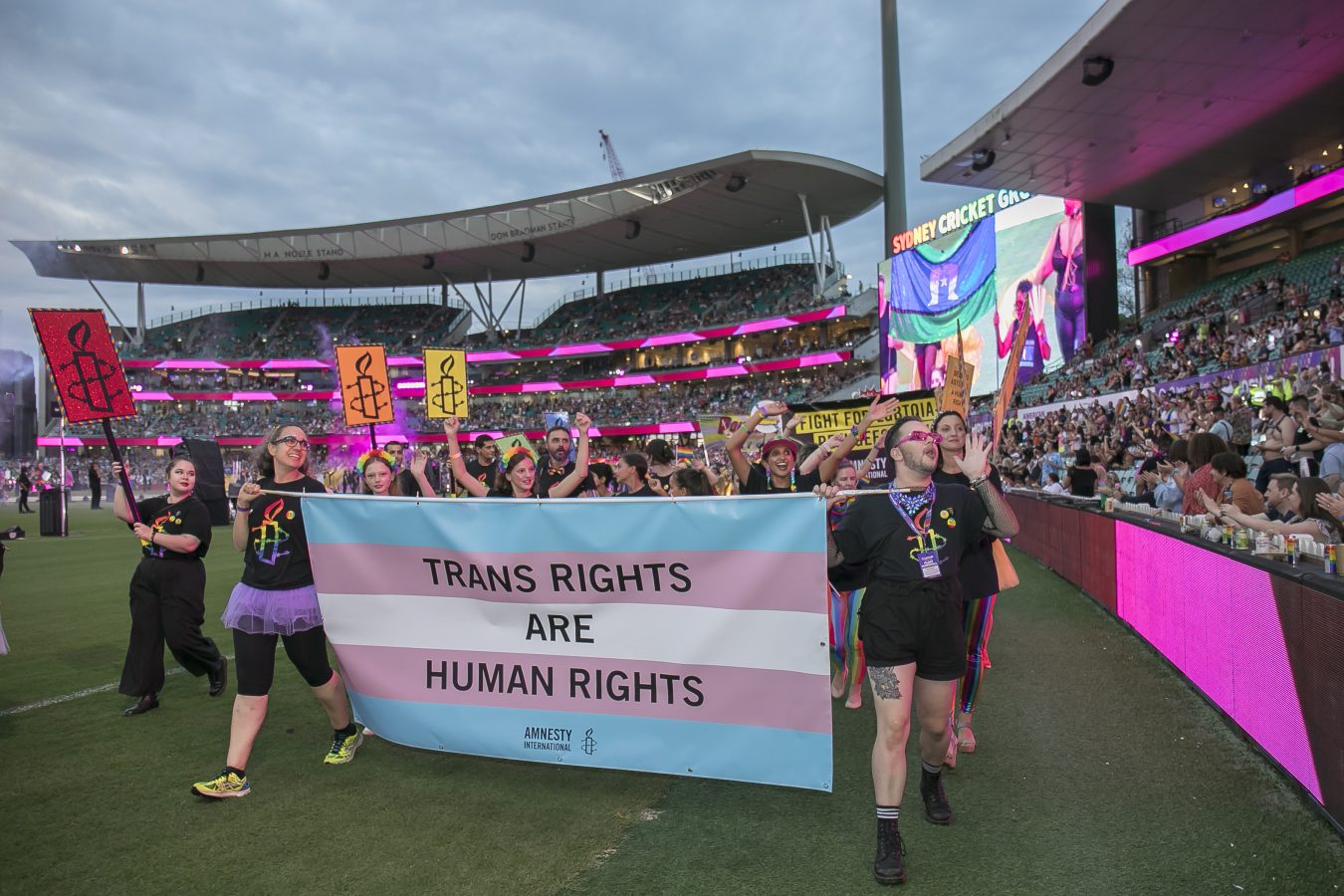 People marching holding the trans flag with the words - Trans Rights are Human Rights