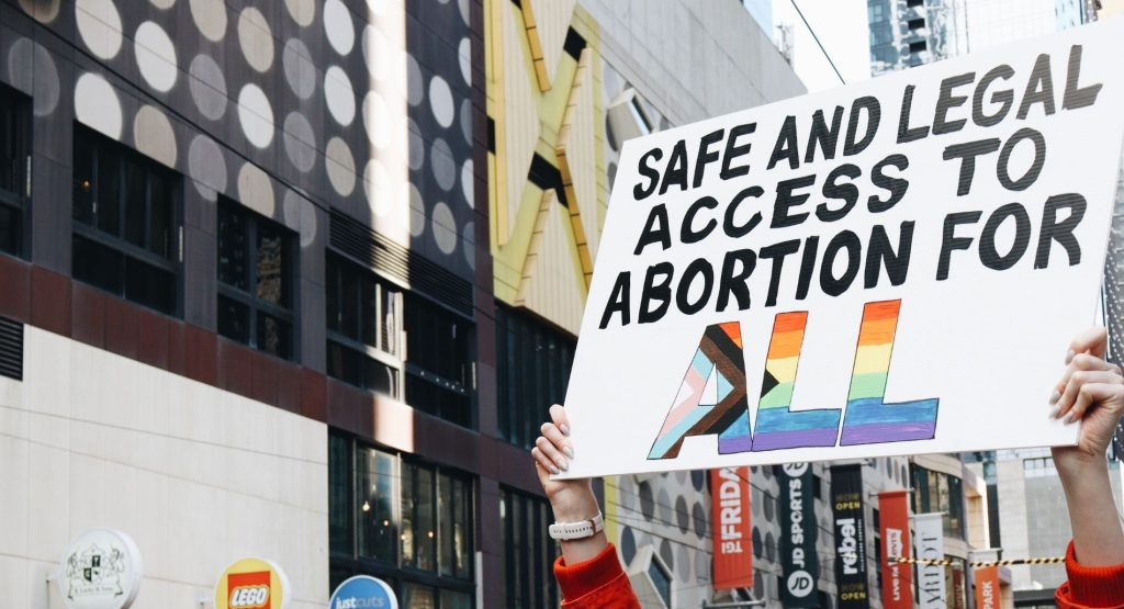 A protester holds a sign that reads "safe and legal access to abortion for all"