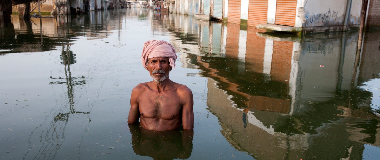 A man stands chest-deep in flood waters in Pakistan