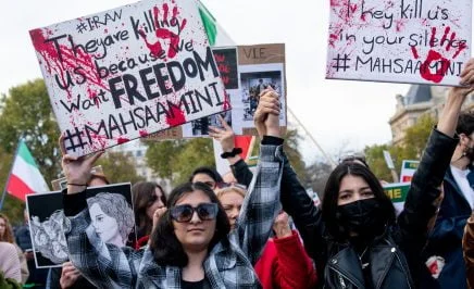 Women taking to the streets in Iran holding signs that say 'They are killing us because we want freedom'