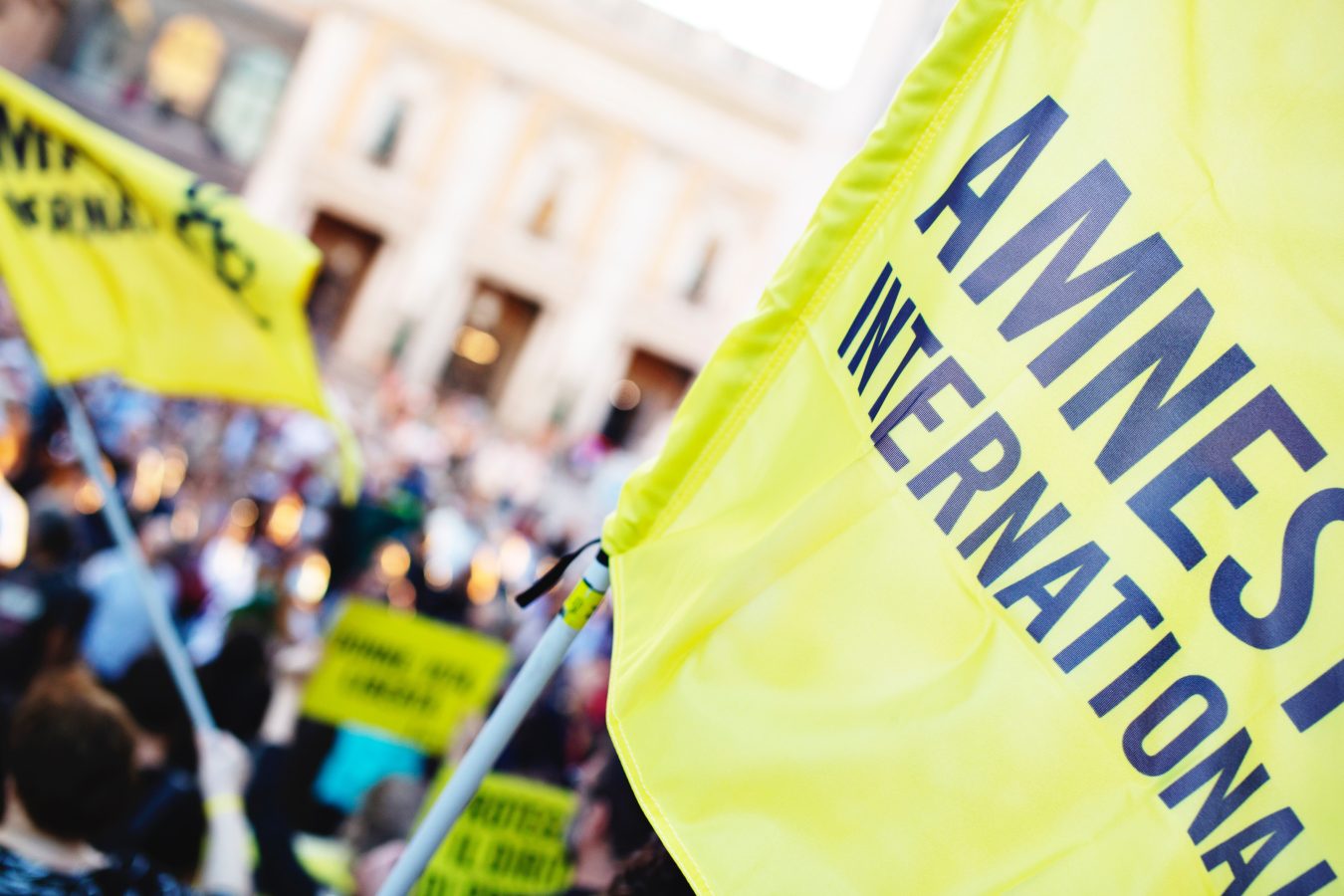 A close up of the Amnesty International flag someone is waving as part of a protest.