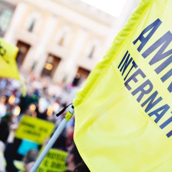 A close up of the Amnesty International flag someone is waving as part of a protest.