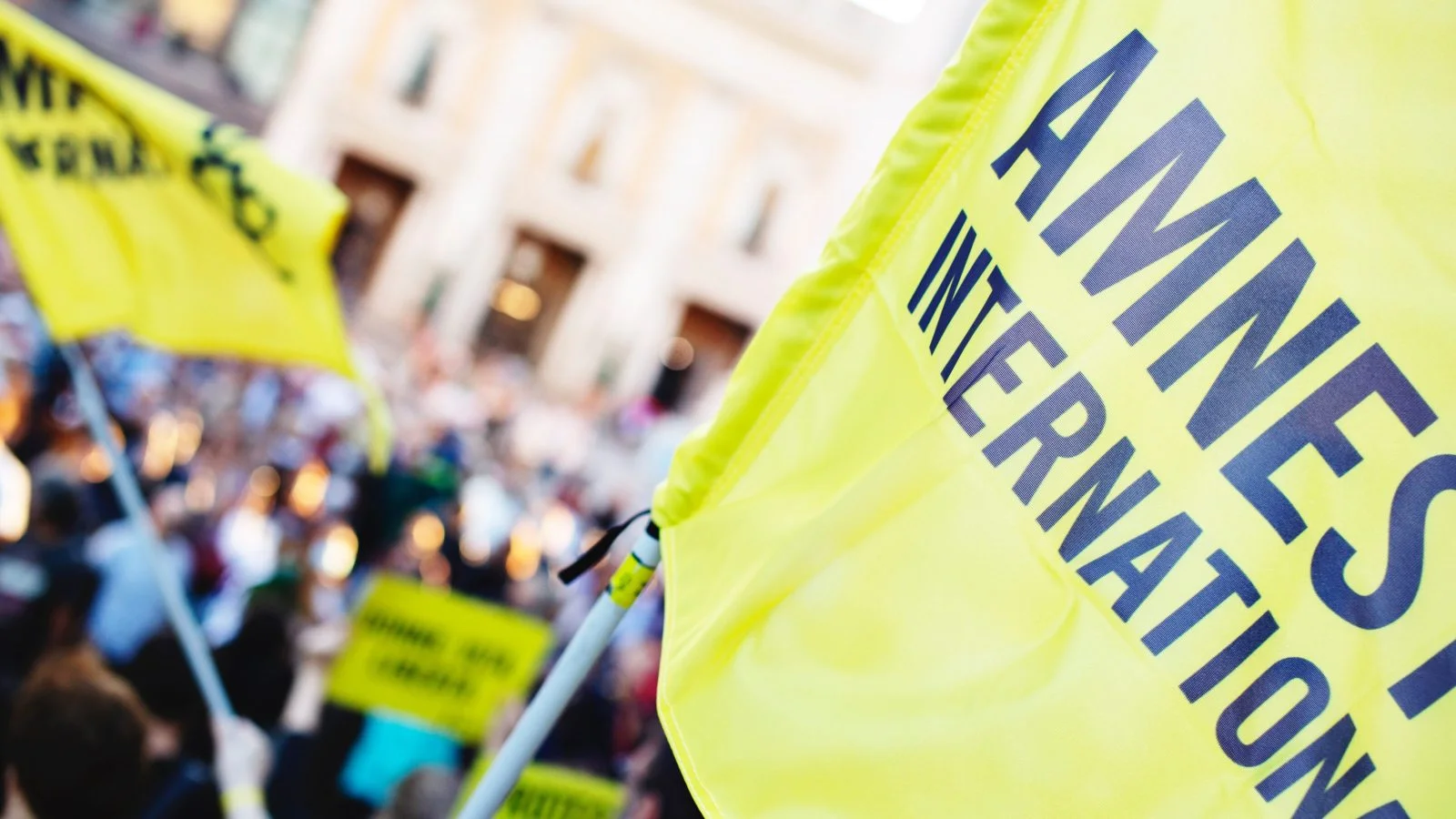 A close up of the Amnesty International flag someone is waving as part of a protest.