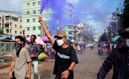 A young demonstrator lights a flare during an anti-coup protest.