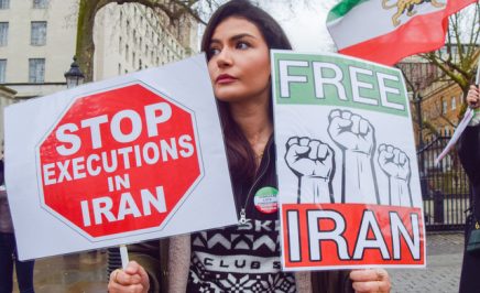A protester holds 'Stop executions in Iran' and 'Free Iran' placards