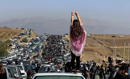 This 26 October, 2022, dated image posted on Twitter shows an unveiled woman standing on top of a vehicle as thousands make their way toward Aichi cemetery in Saqez, Mahsa Amini's hometown in the western Iranian province of Kurdistan, to mark 40 days since her death.